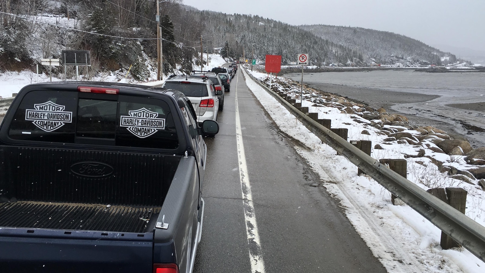 Une longue file de véhicules sur le bord du fleuve.