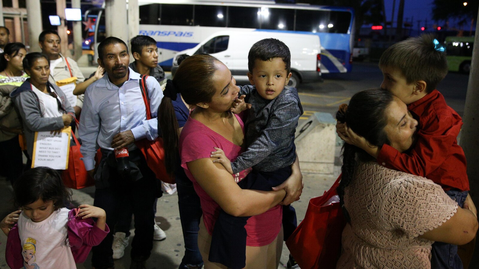 Des immigrants sans papier récemment libérés grâce à la politique « attraper et relâcher » font la file en attendant de monter à bord d'un bus à McAllen, au Texas.