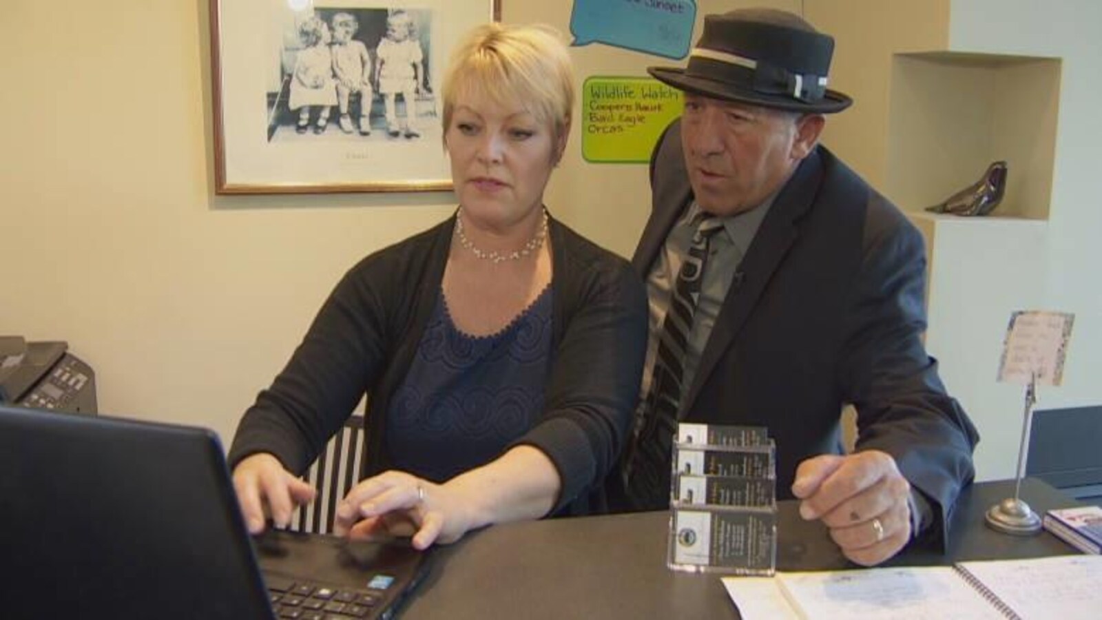 Un couple regarde un écran d'ordinateur à la réception d'un hôtel.