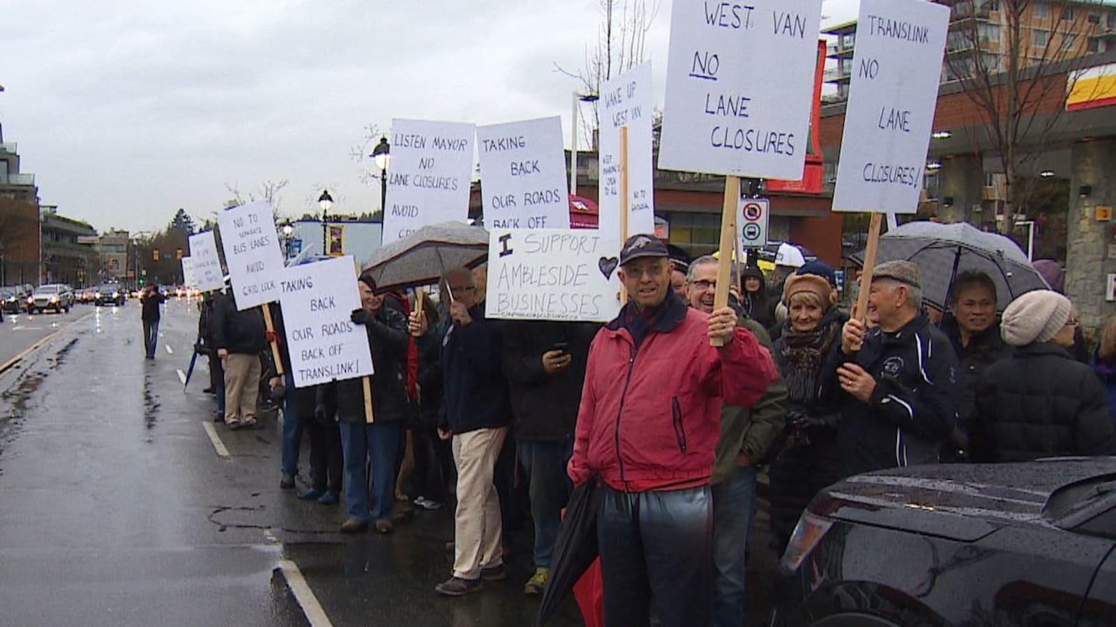 Des dizaines de manifestants debout sous la pluie dénoncent la proposition d'un nouveau couloir de bus à West Vancouver
