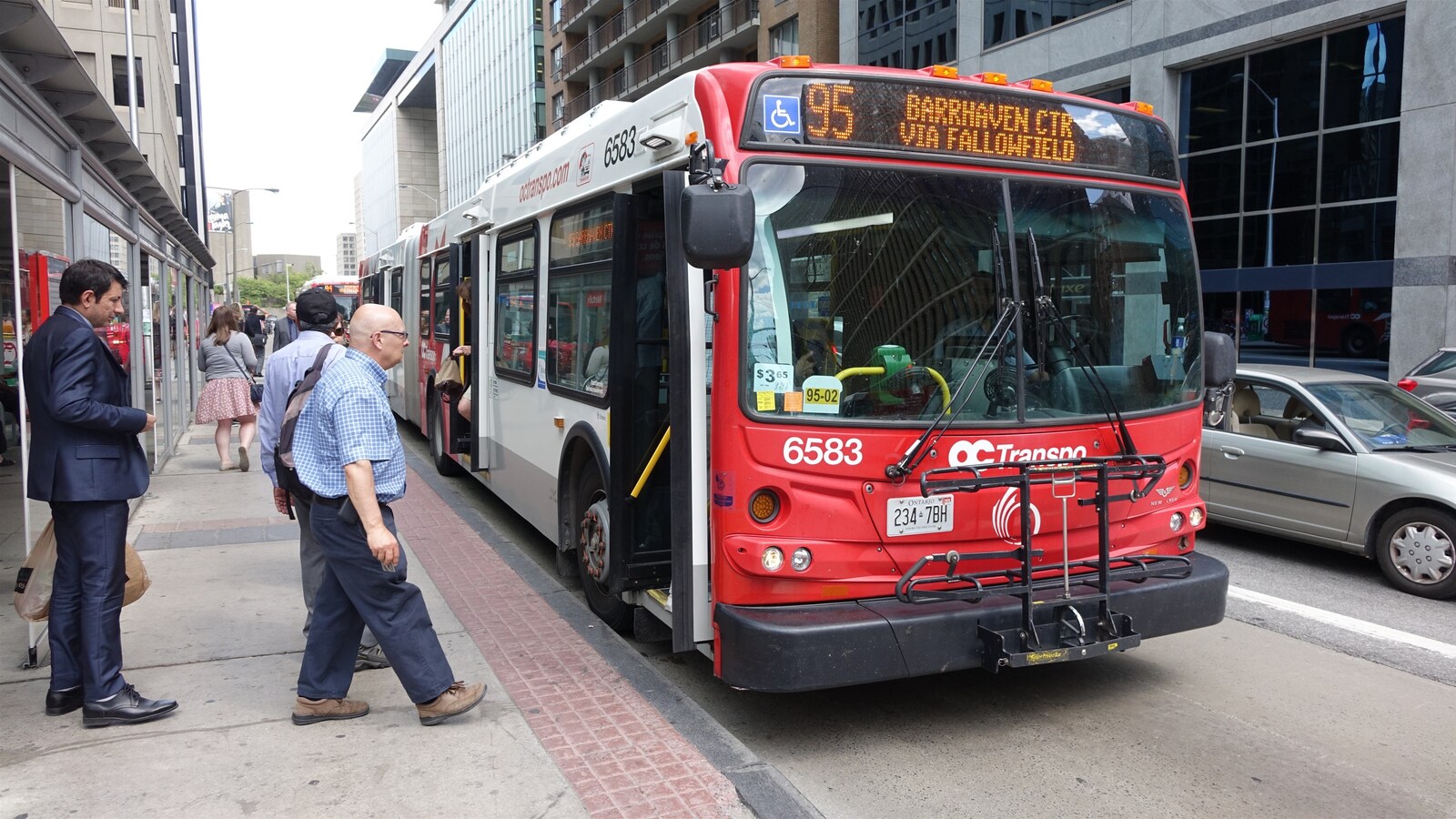 Des personnes se préparent à rentrer à l'intérieur d'un autobus d'OC Transpo.