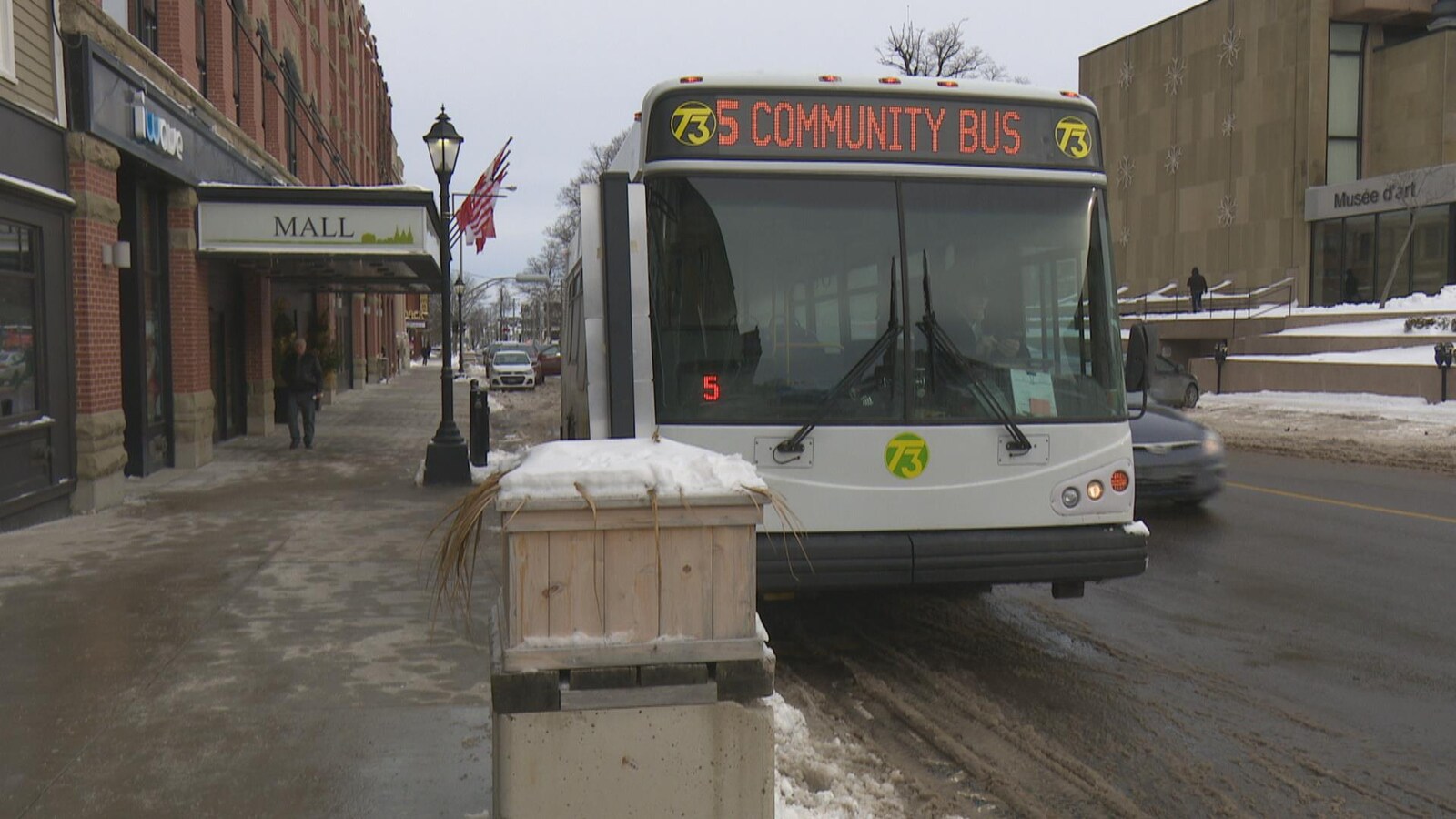 Vue de devant d'un autobus de l'entreprise T3 stationné devant le centre commercial de la Confédération, dans le centre-ville de Charlottetown.
