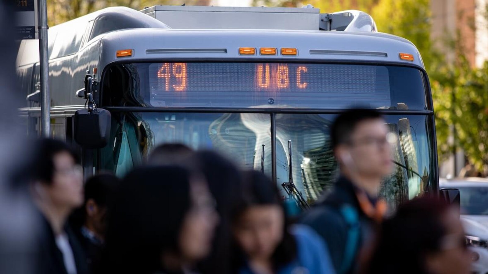 Un autobus avec le numéro 49 est arrêté. Des gens attendent à un arrêt.