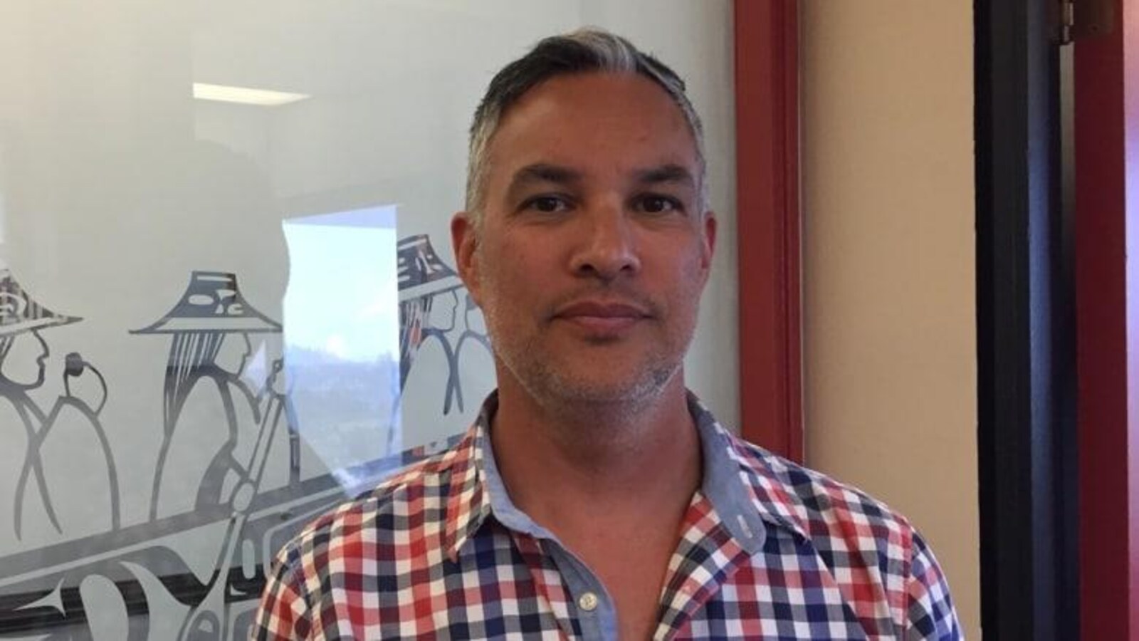 Un homme autochtone vêtu d'une chemise pose, sans sourire.