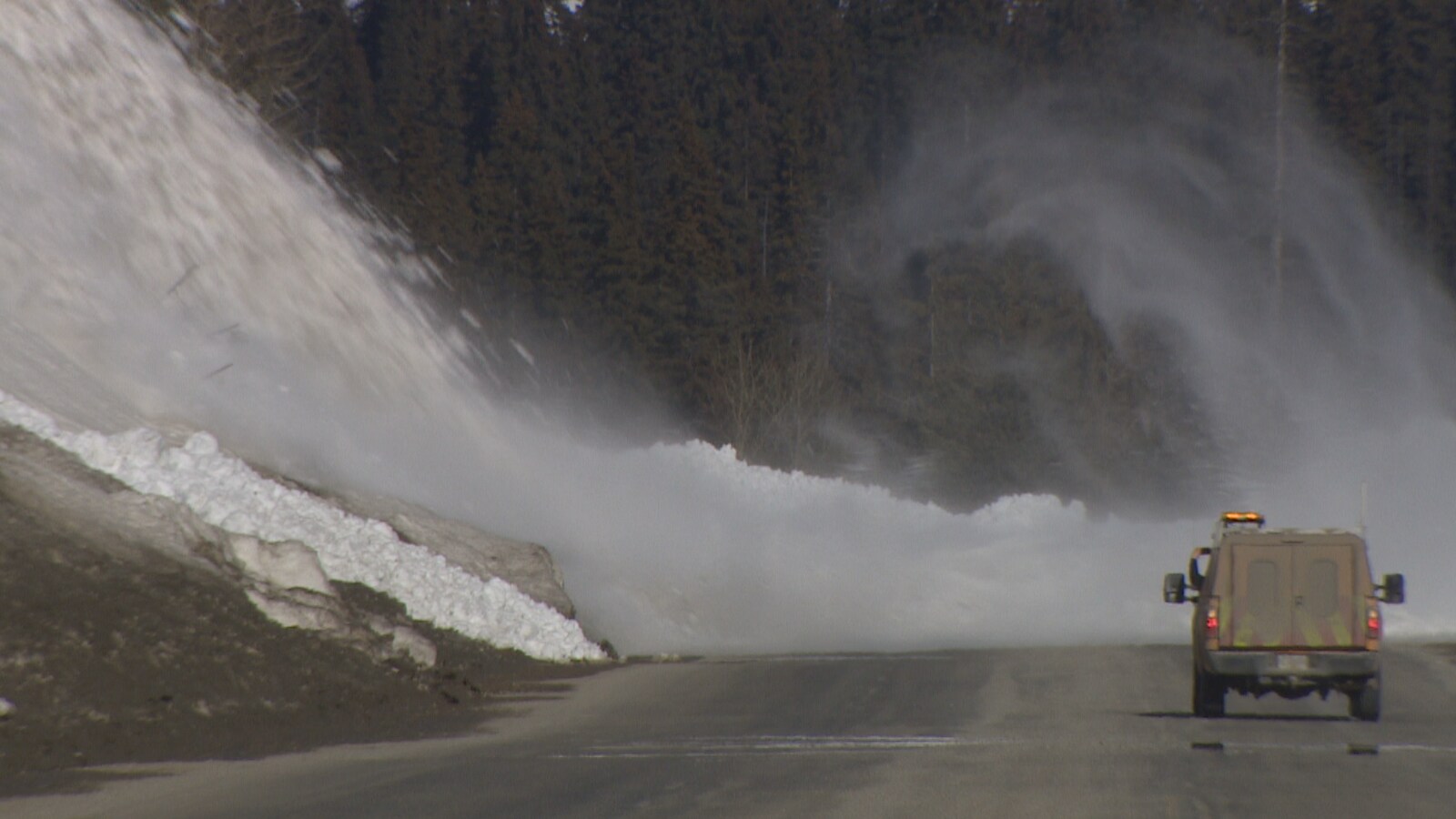 La neige finit sa trajectoire sur l'asphalte et un véhicule se tient à distance