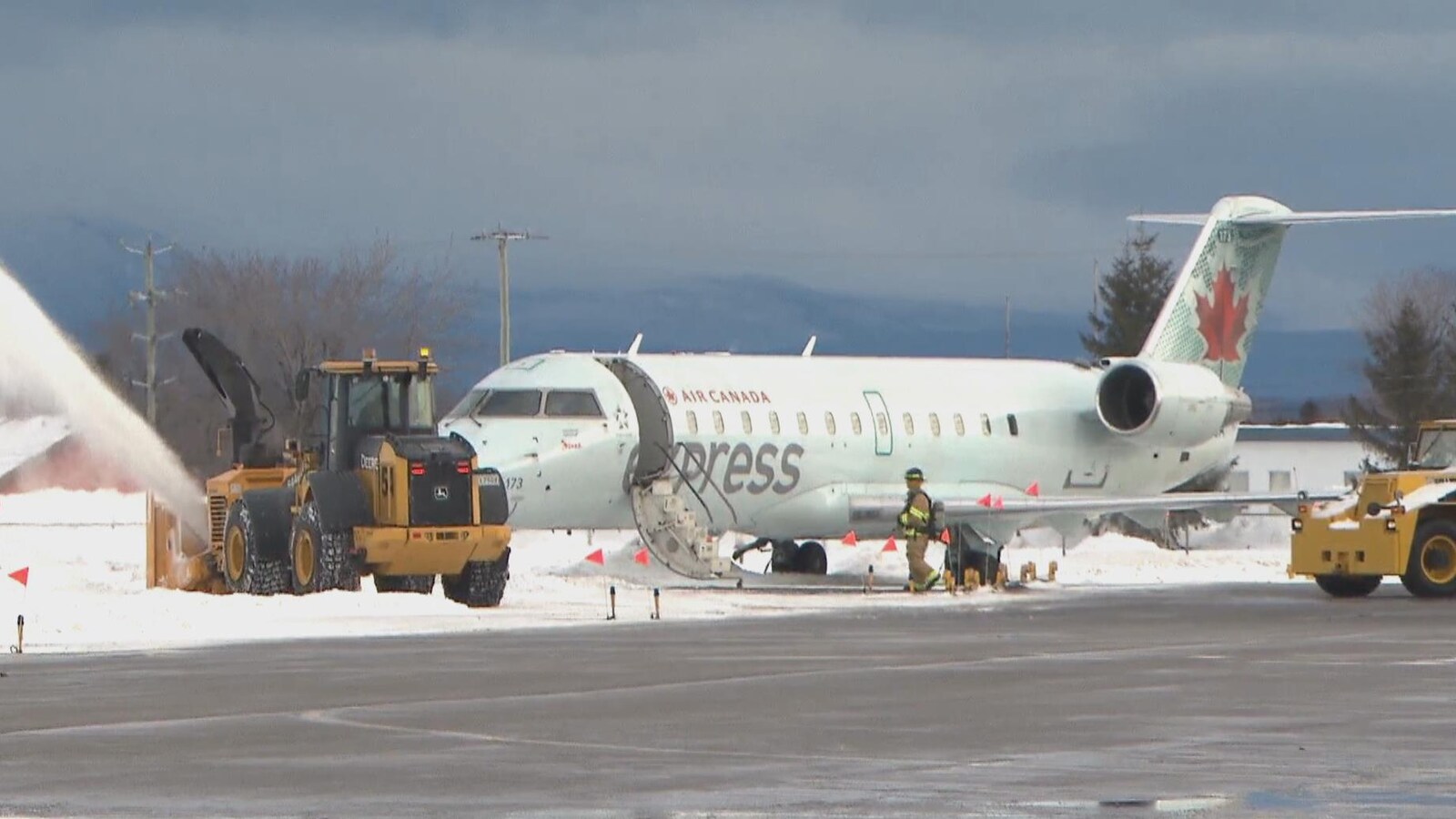 Un pompier inspecte l'avion d'Air Canada qui a sorti de piste.