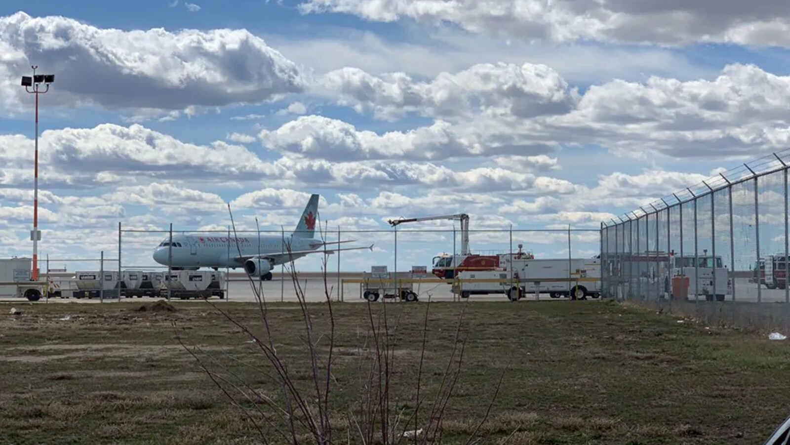 Un avion d'Air Canada sur une piste de l'aéroport de Regina avec des équipes de services d'incendie qui sont tout près.
