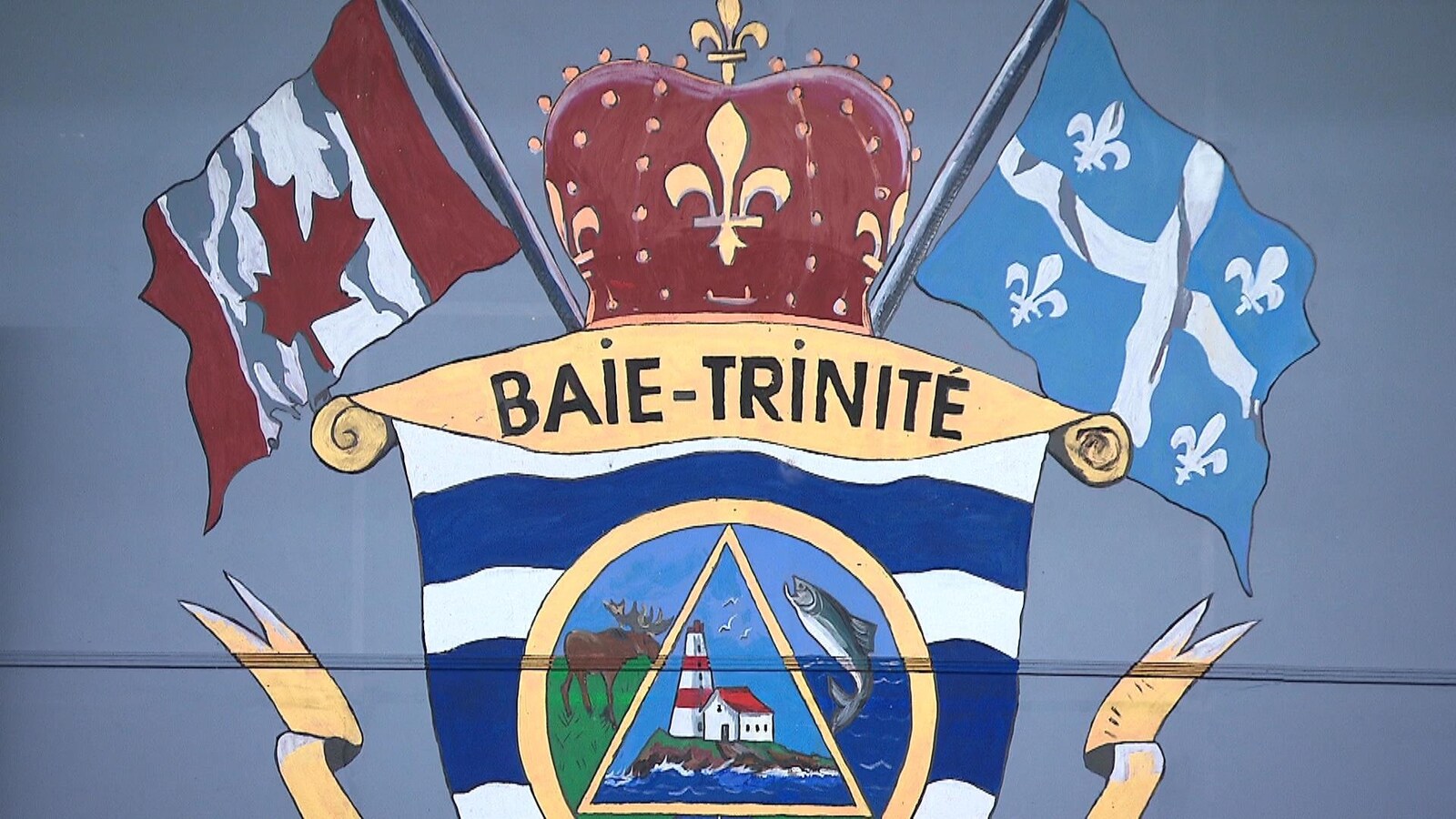 Les armoiries de la Municipalité du village de Baie-Trinité représentent les drapeaux, un orignal, un poisson et un phare. Elles sont peintes sur un mur dans la salle de réunion.