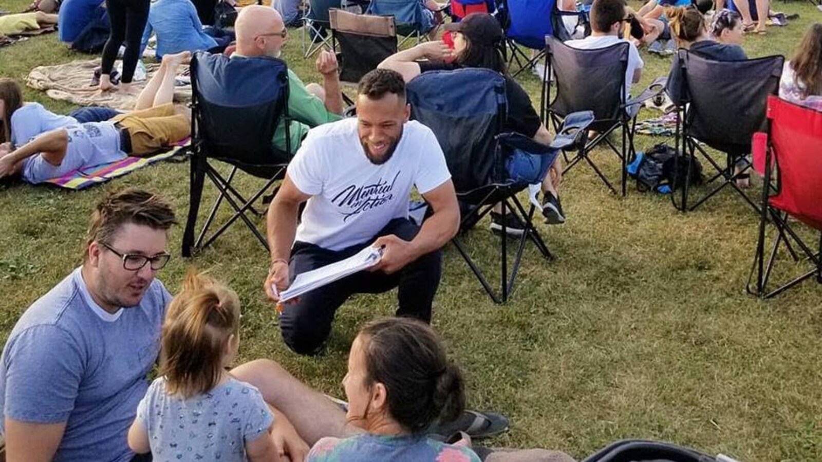 Un homme accroupi pour faire signer une pétition.