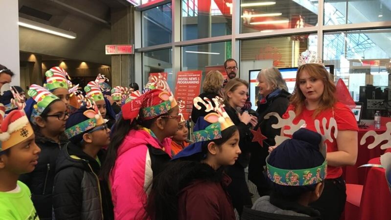 Des enfants écoutent la reporter météo Sarah Murphy dans la salle de nouvelle de Radio-Canada