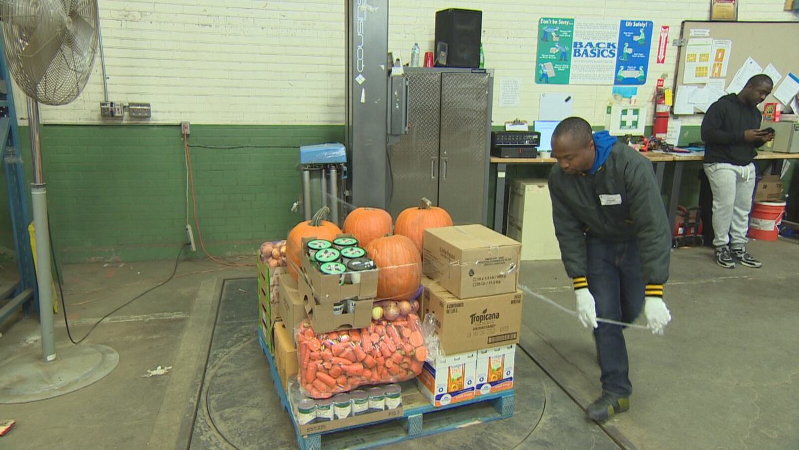 Photo d'un homme qui enlève un ruban autocollant autour de boîtes de nourriture et de citrouilles.