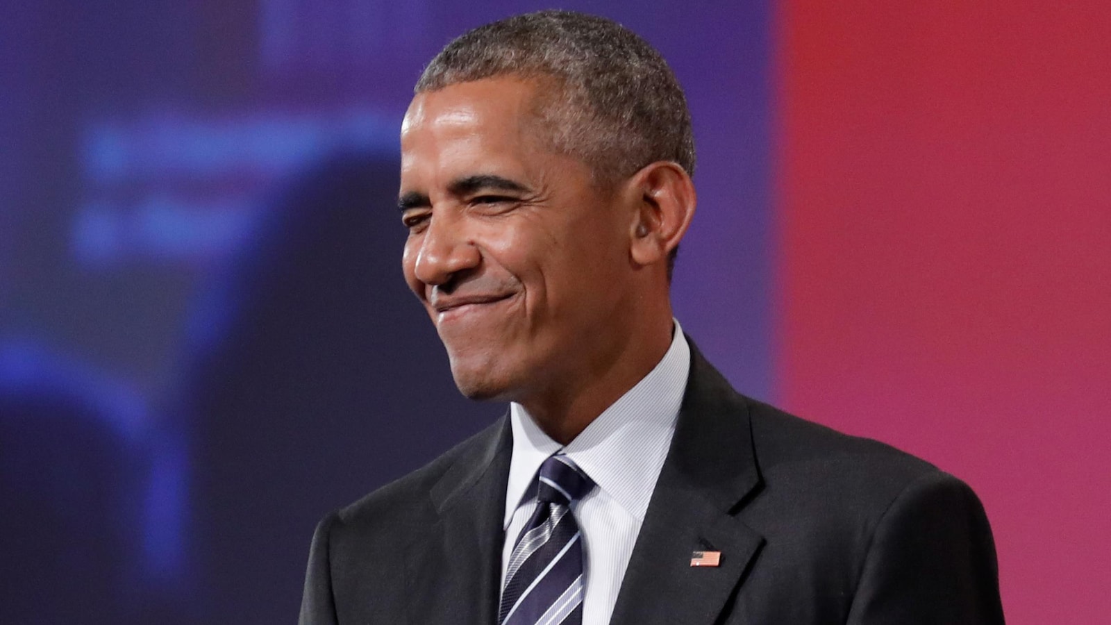 L'ancien président américain Barack Obama affiche un large sourire et des yeux rieurs.