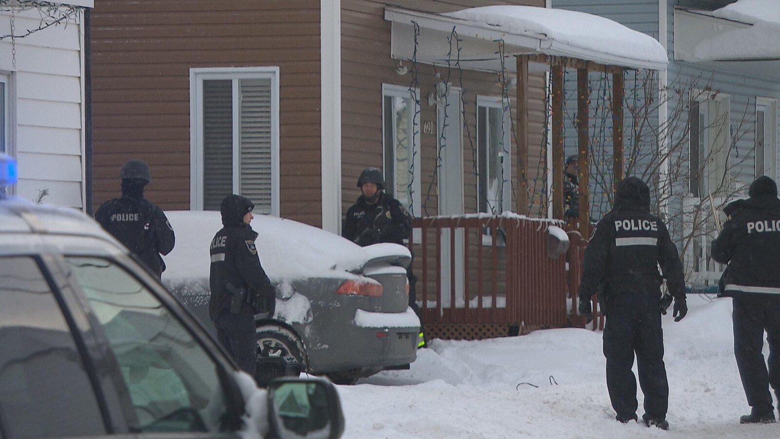 Des policiers placés autour d'une maison en hiver