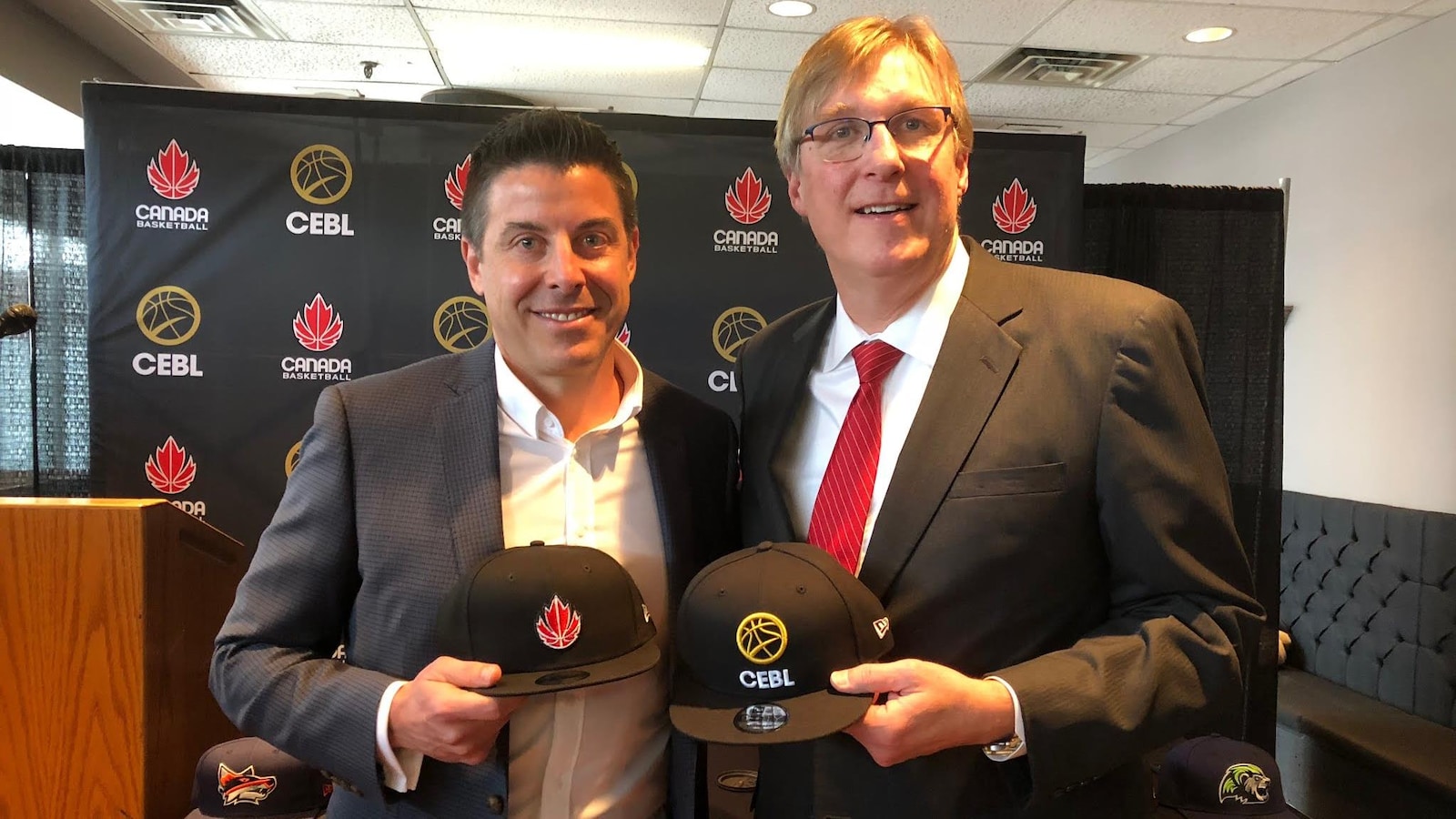 Deux hommes tiennent deux casquettes.