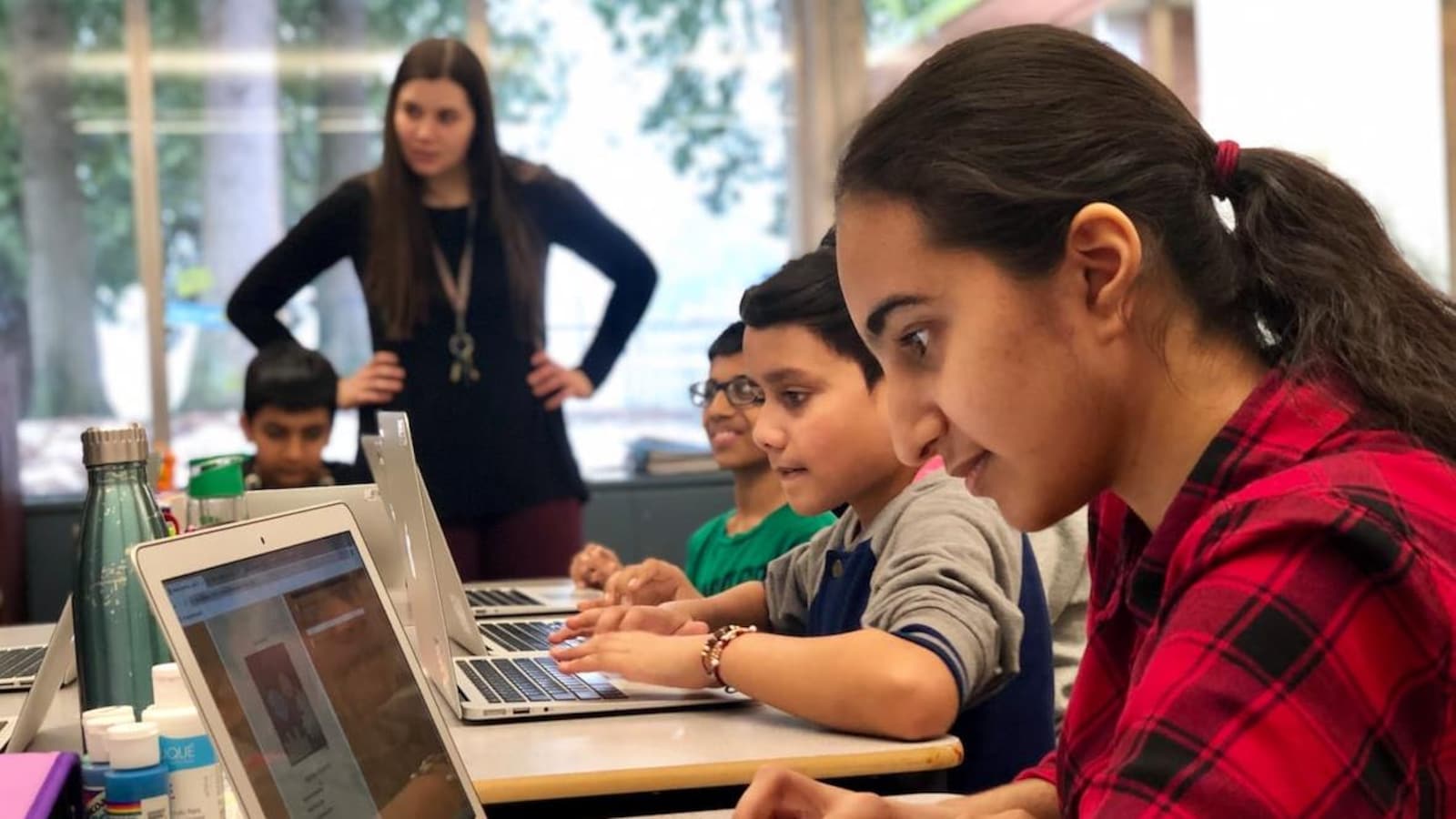 Une jeune fille regarde un ordinateur dans une classe.