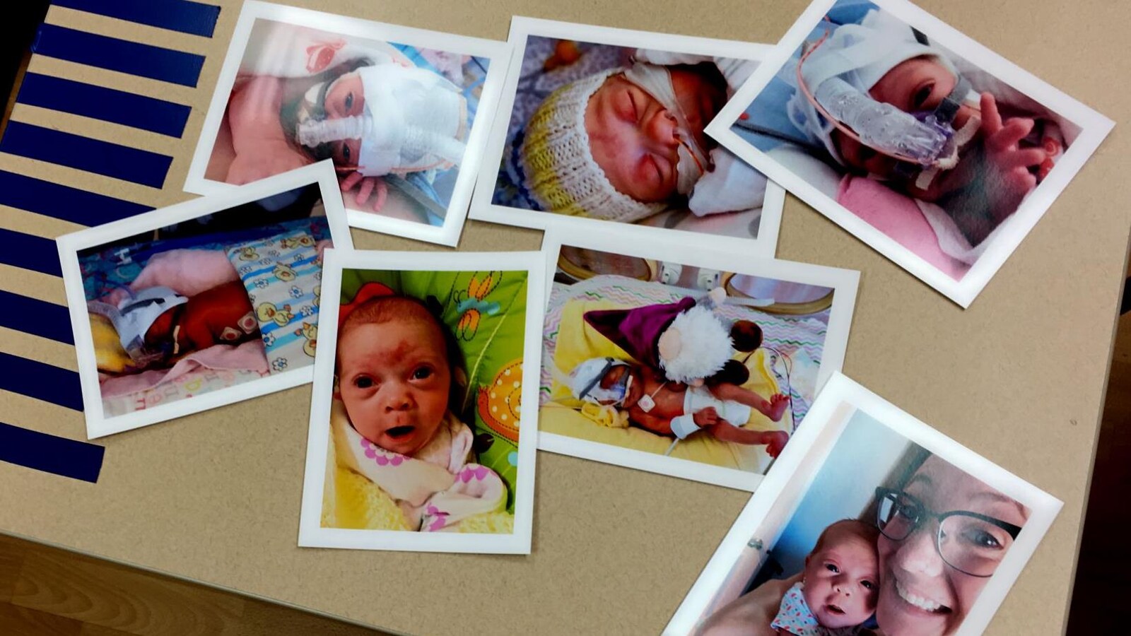 Sept photos d'un bébé prématuré sont disposées pêle-mêle sur une table.