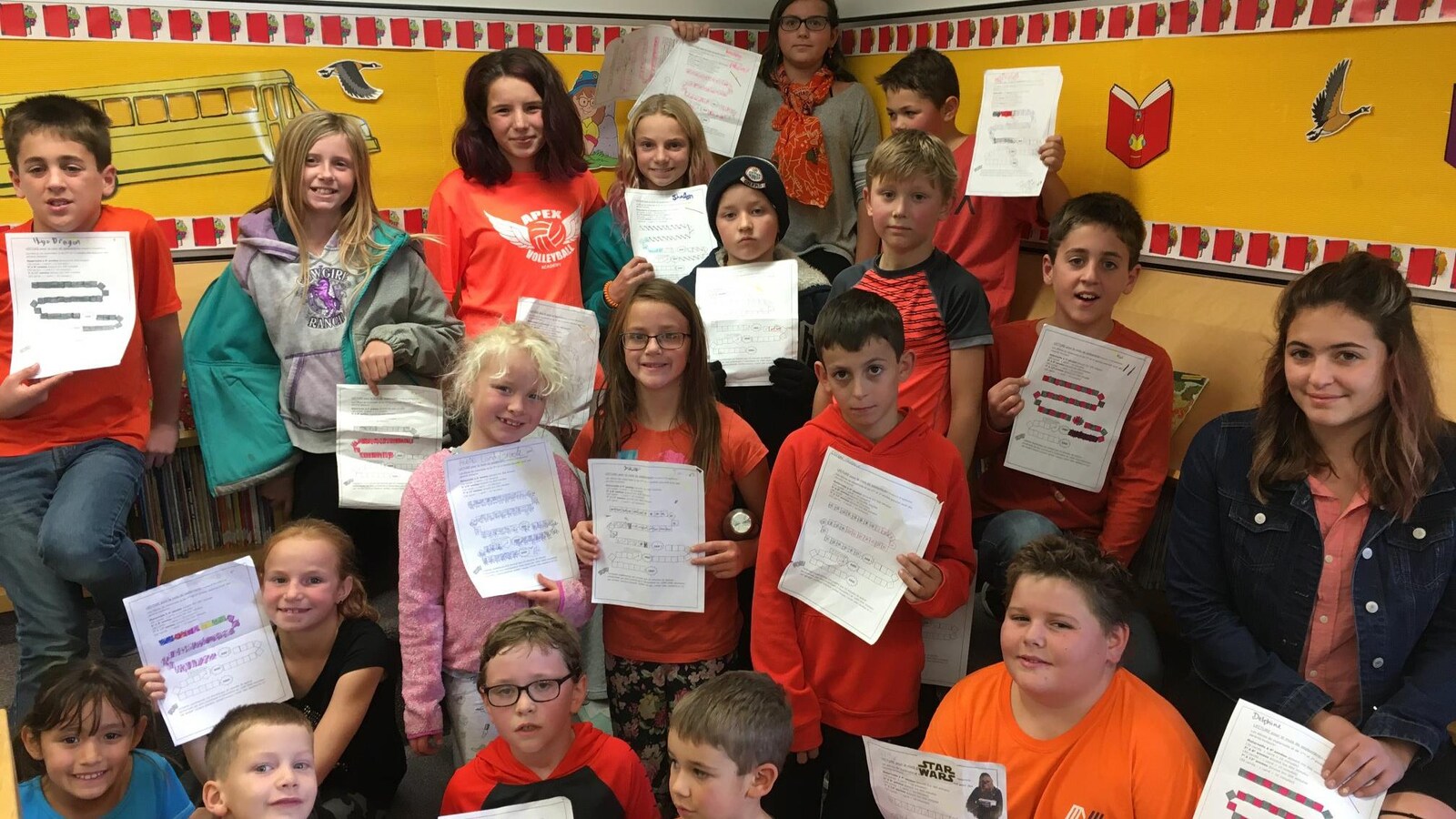 Un groupe d'une vingtaine d'élèves portant des vêtements de couleur orange montre une feuille de papier qui affiche le nombre de minutes de lecture qu'ils ont faite.