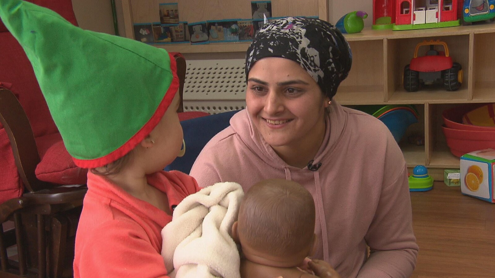 La dame qui regarde un enfant qui a un bébé jouet dans les mains.