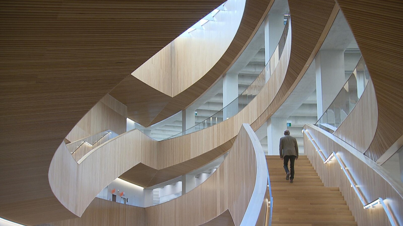 Un homme monte les marches d'un escalier en bois de la nouvelle bibliothèque centrale de Calgary.