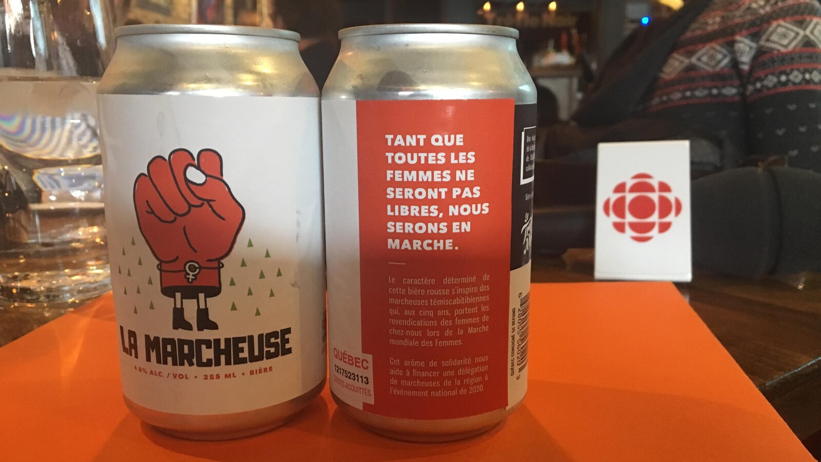 Deux canettes de bière avec un logo en forme de poing levé intitulées La Marcheuse.