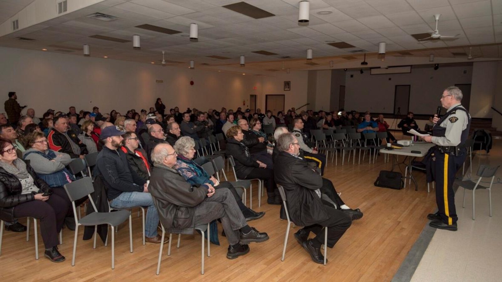 s’adresse aux participants présents à l’assemblée publique.