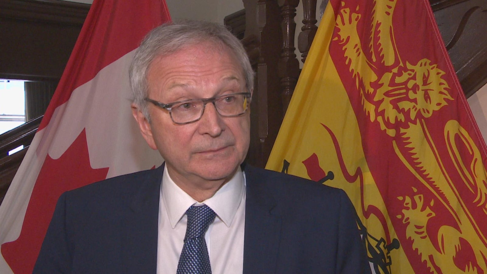 Blaine Higgs le 15 mai 2019 à l'Assemblée législative devant des drapeaux du Nouveau-Brunswick et du Canada.