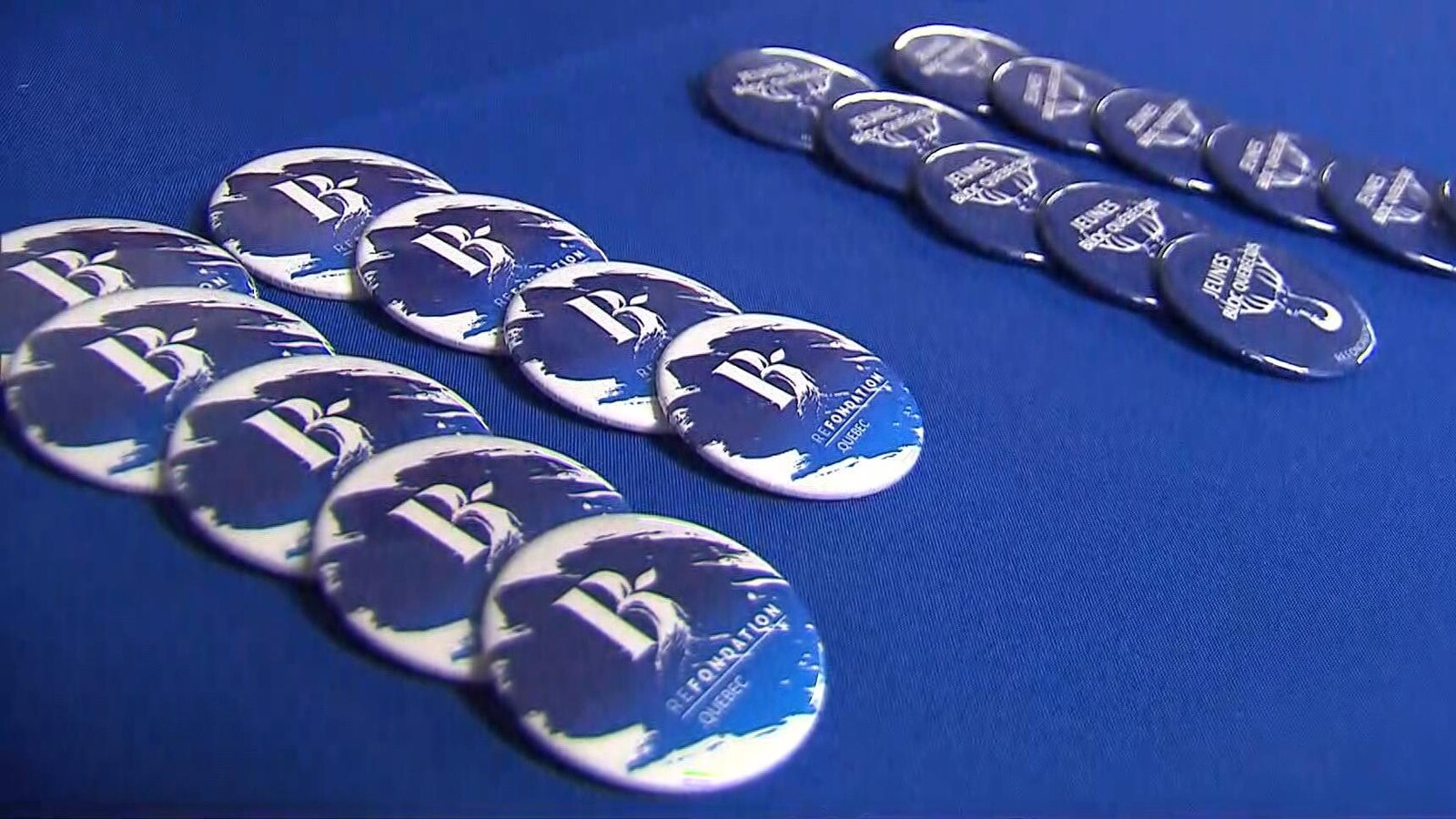 Des macarons du Bloc québécois sont alignés sur une table.