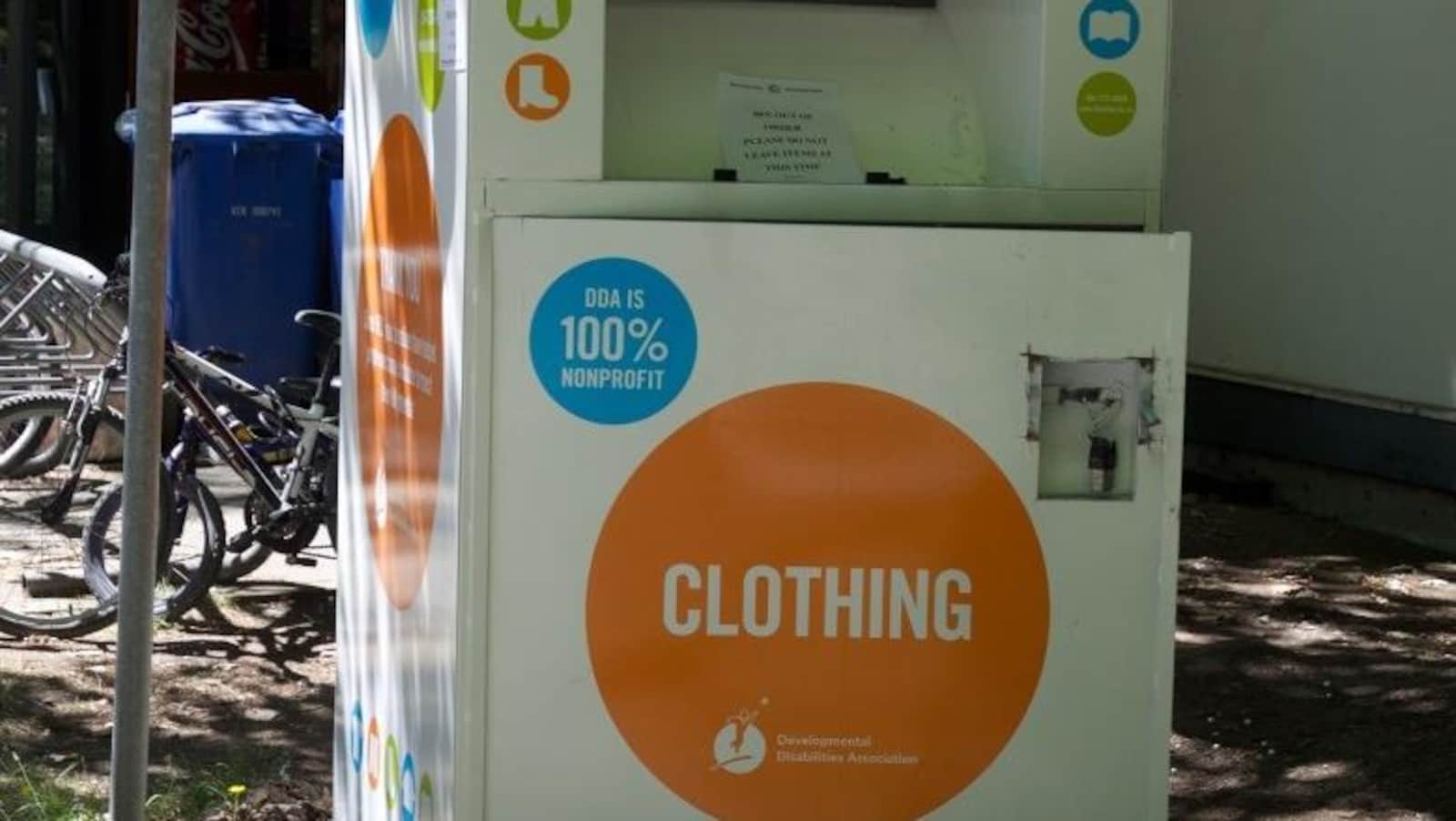 une boîte de dons pour vêtements, à côté d'un poteau et d'un support à vélo.
