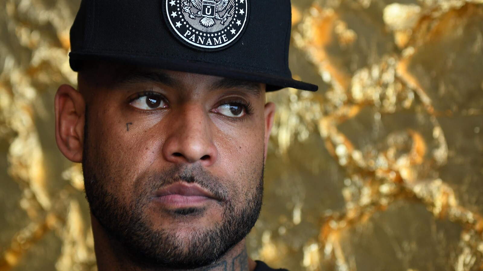 Le rappeur français Booba, portant une casquette noire, regarde sur le côté.