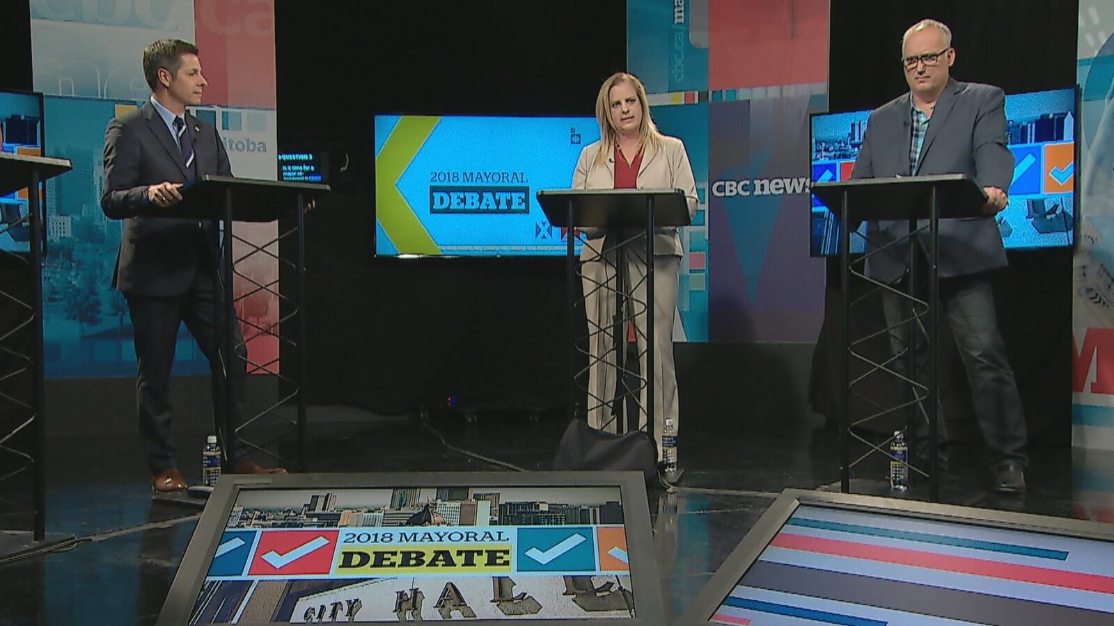 Les trois candidats derrière des lutrins, dans un studio de télévision.