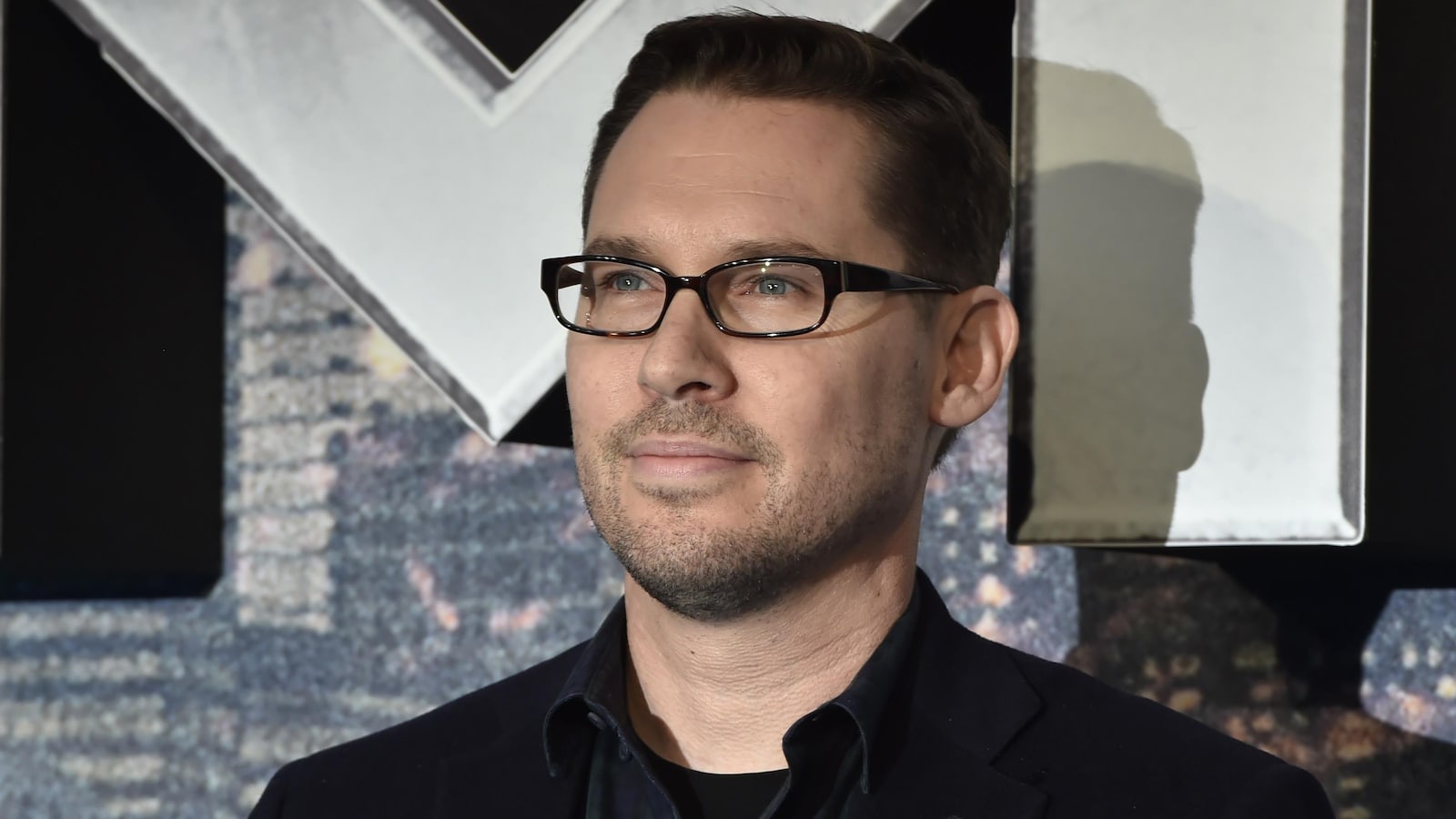 Le réalisateur Bryan Singer prend la pose sur le tapis rouge du film X-Men Apocalypse, en 2016.