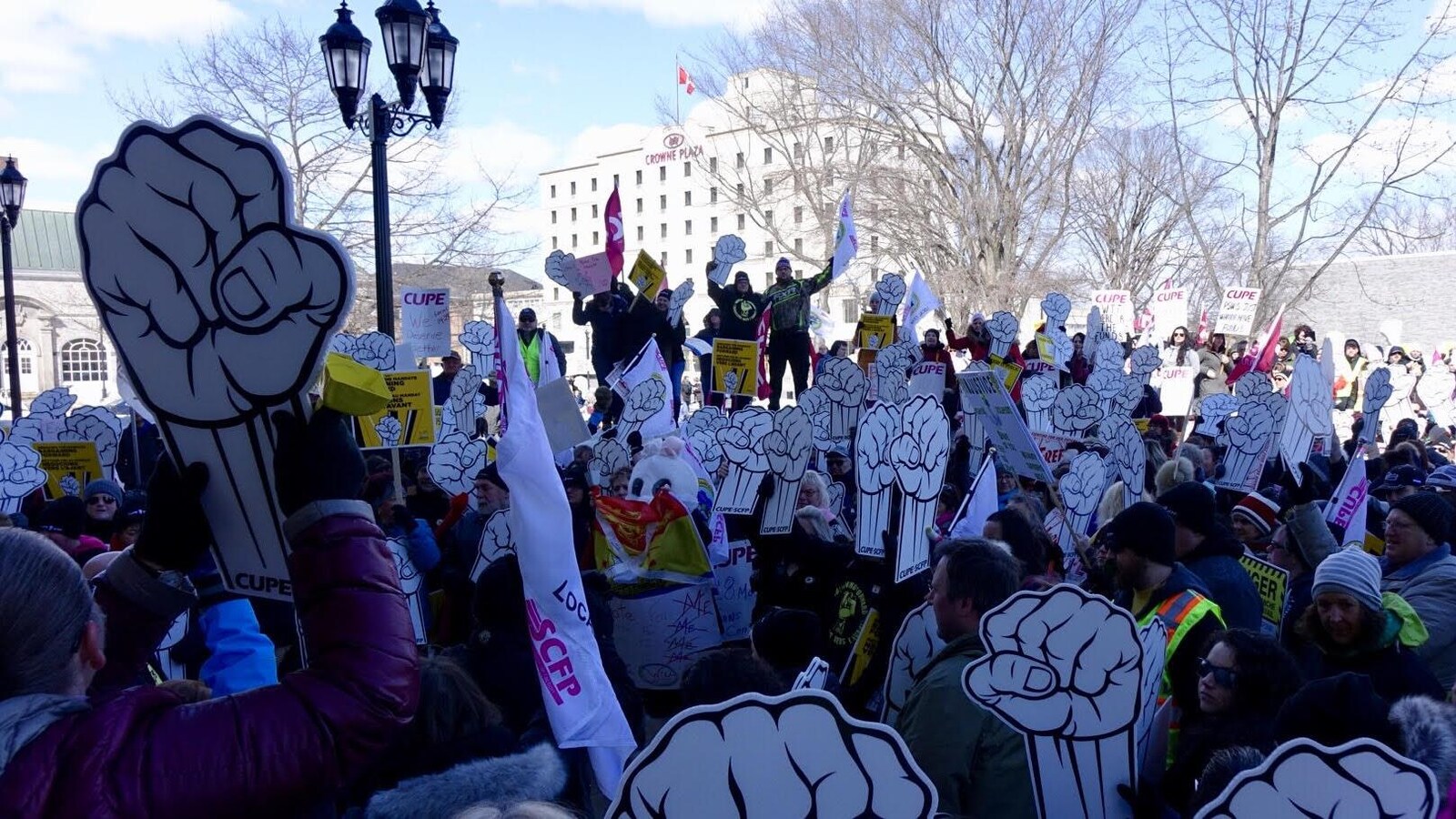 Les manifestants brandissent de grandes pancartes en forme de poing levé.