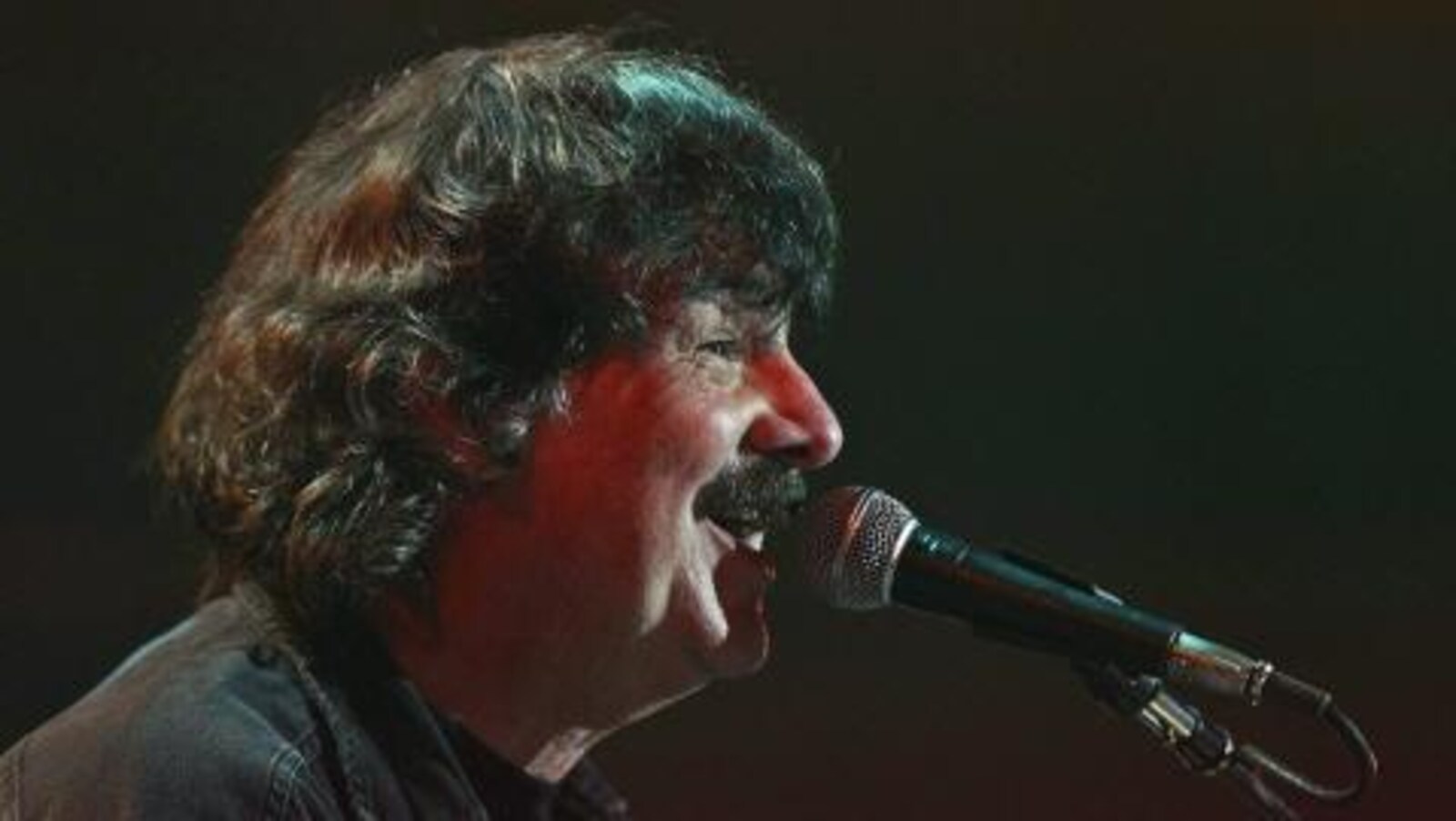 Burton Cummings, devant un micro, chante pendant un concert.