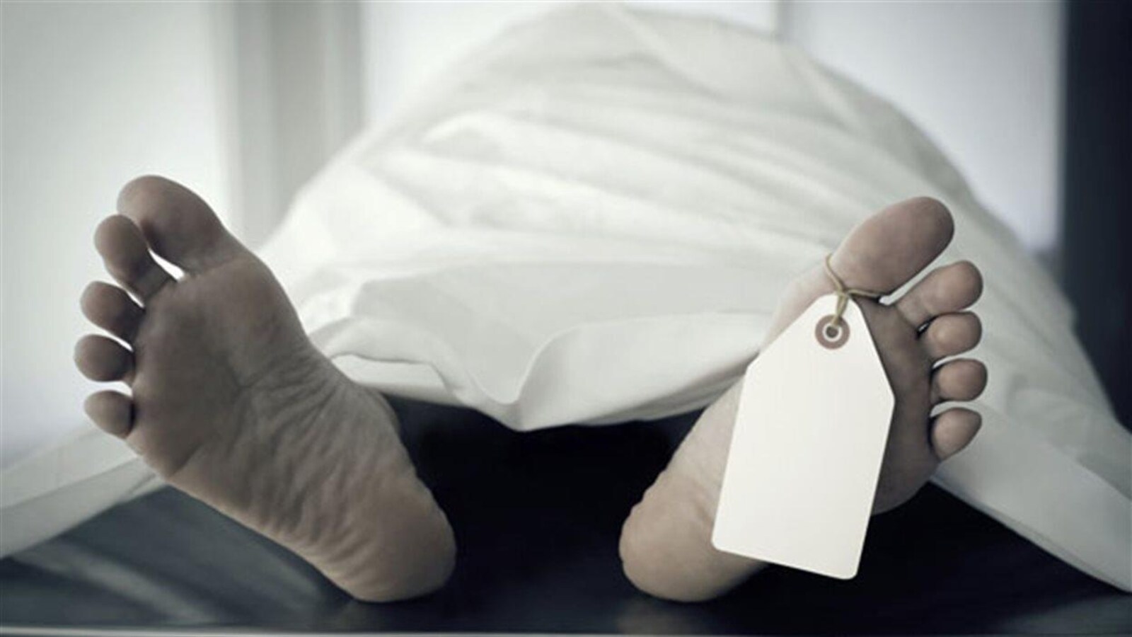 Corps recouvert d'un drap où l'on voit les pieds et une étiquette attachée à un orteil