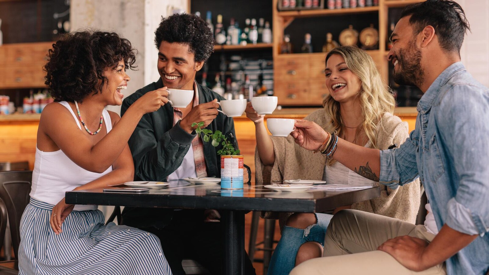 Quatre personnes boivent du café autour d'une table.