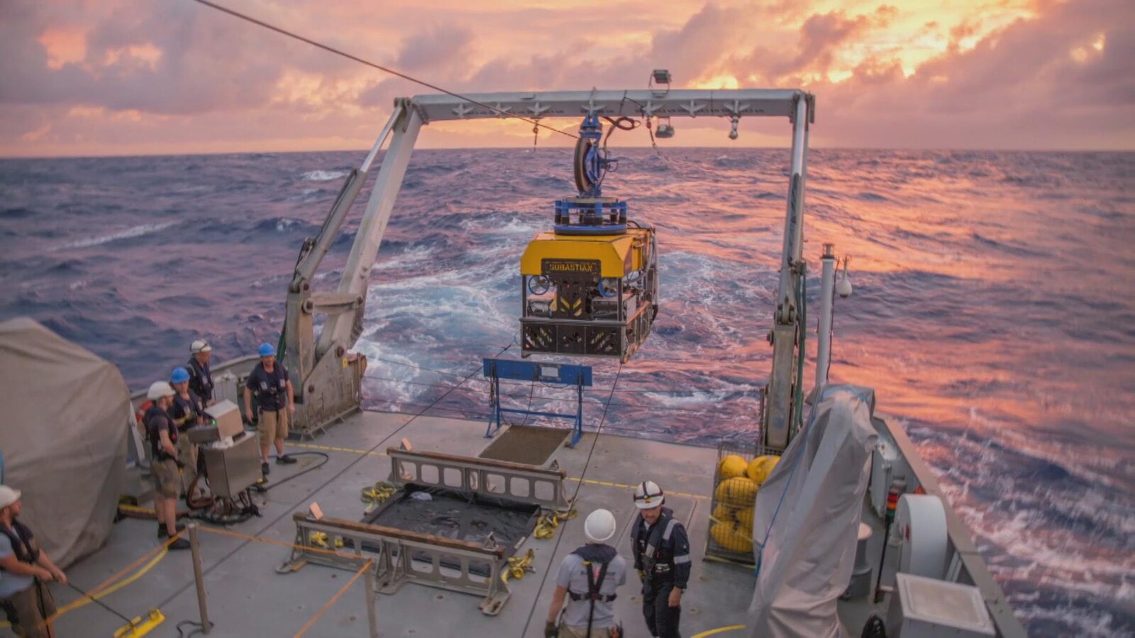 L'équipage d'un bateau s'apprête à mettre à l'eau un robot de recherche.