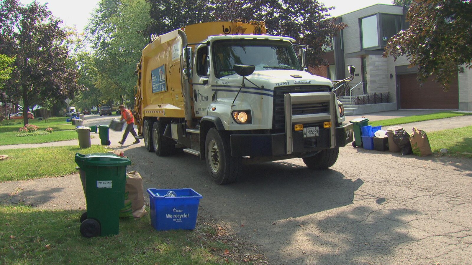 Un camion-poubelle de la Ville d'Ottawa circule dans une rue résidentielle.