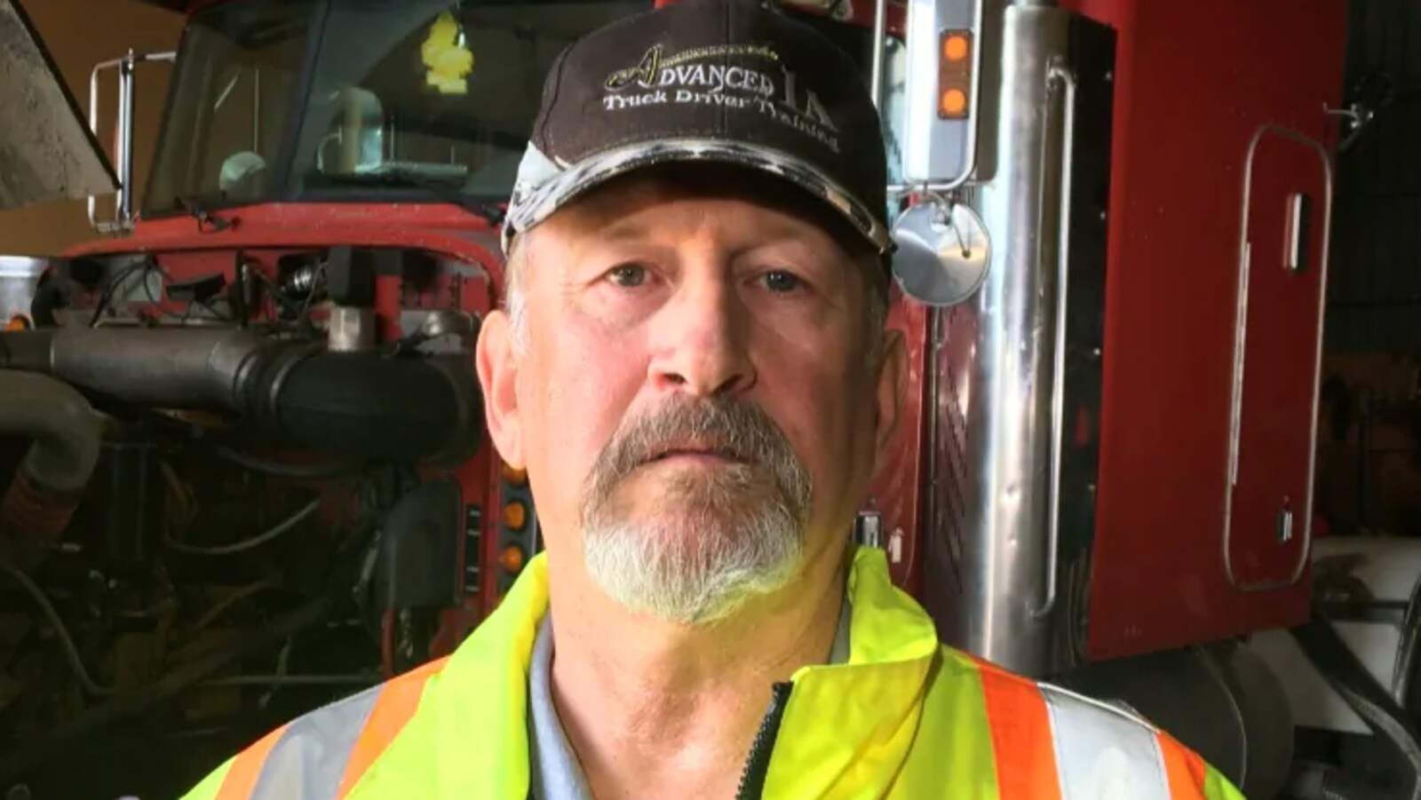Le formateur de conduite Reg Lewis pose devant un camion.