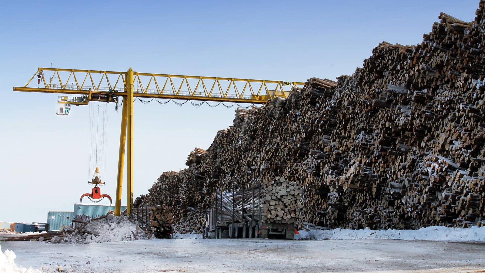 Des camions de billots se font décharger par une grue à Hearst.