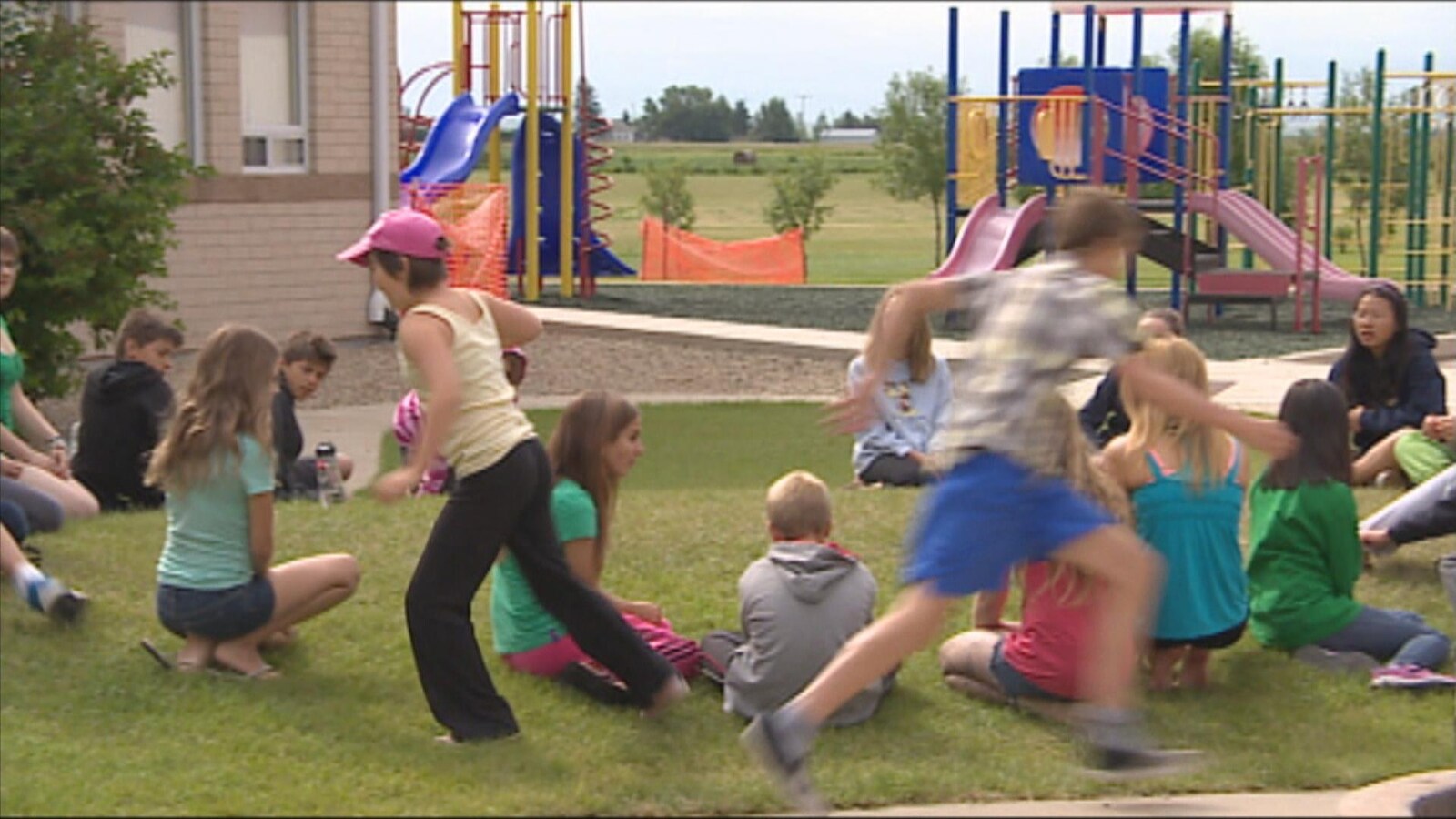 Des jeunes jouent sur un terrain de jeu en plein air durant l'été.