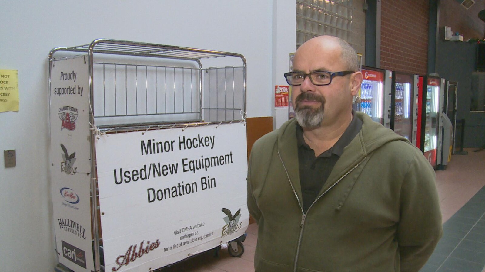 Mark Campbell devant une boîte de dons d'équipement de hockey.
