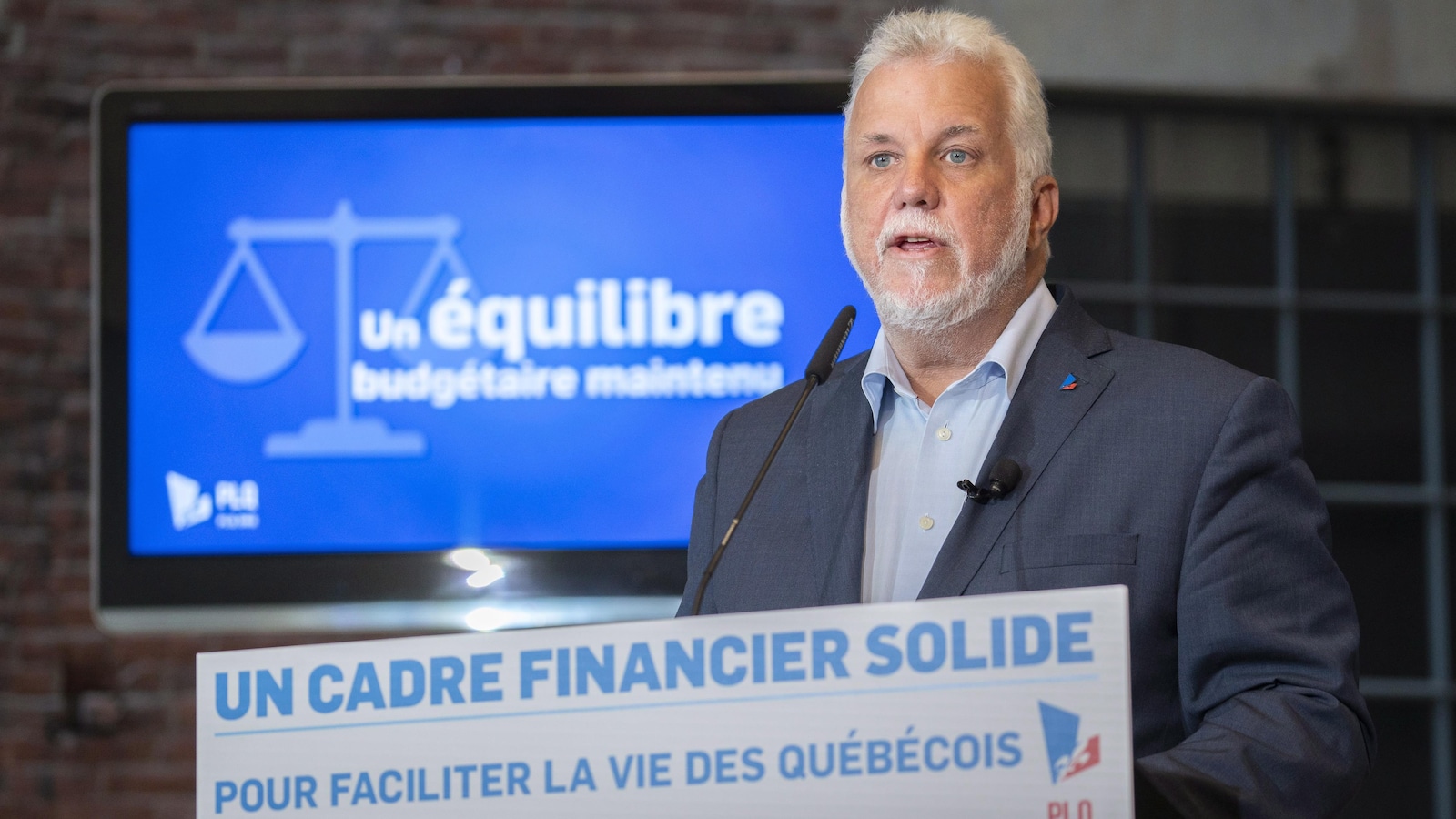 Philippe Couillard devant un lutrin parle dans un micro.