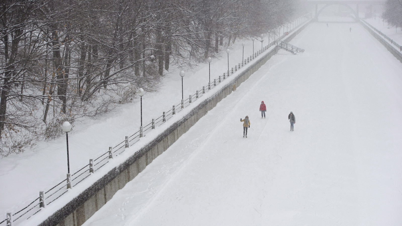 Un groupe de trois personnes marchent sur la glace du canal Rideau, en pleine tempête de neige, en janvier 2018.