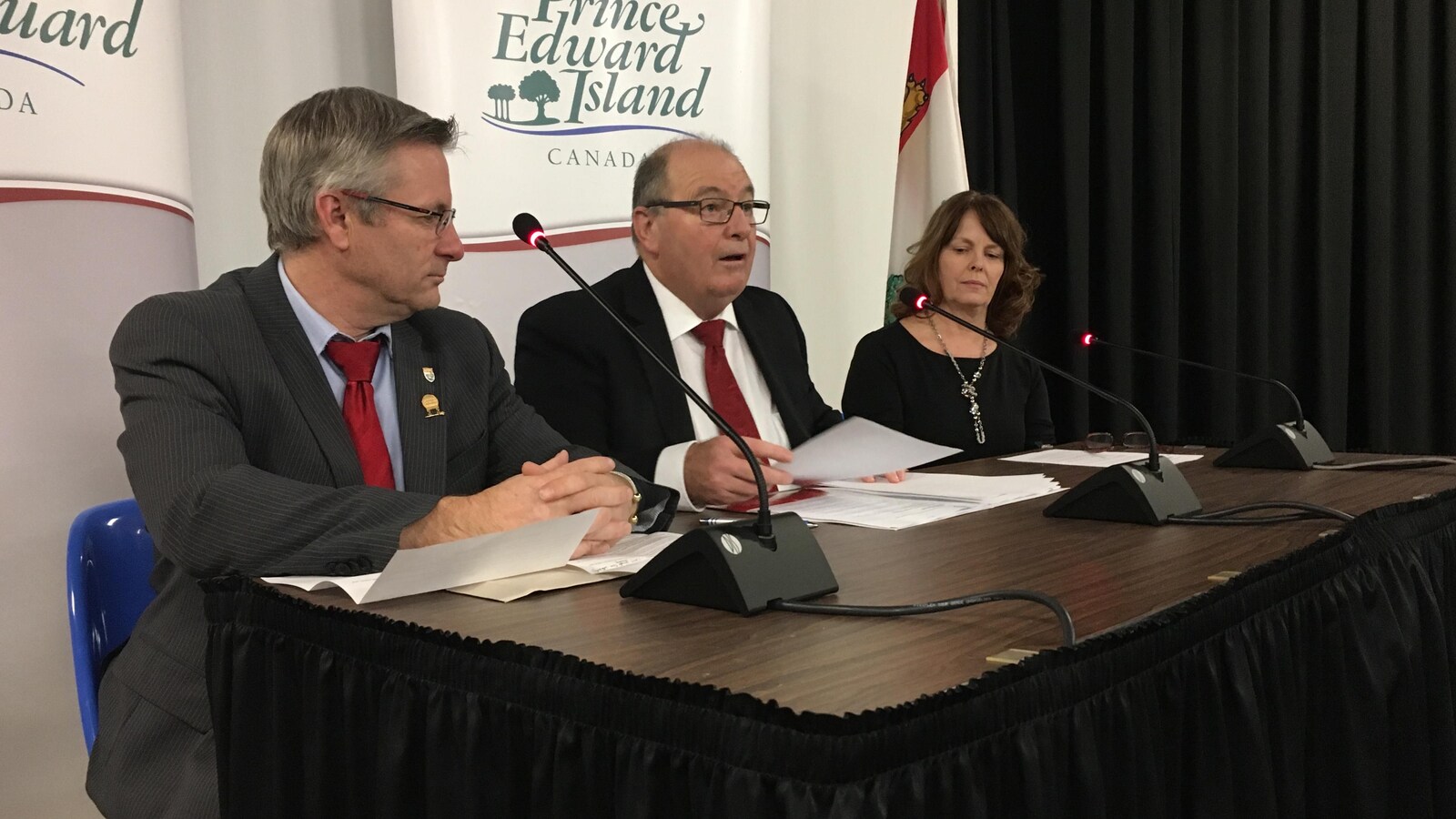 Le ministre Allen Roach entouré de deux autres intervenants