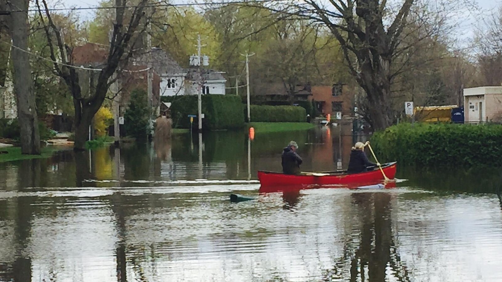 Deux personnes se promènent en canot sur la 13e avenue inondée, à Deux-Montagnes, dans les Laurentides.