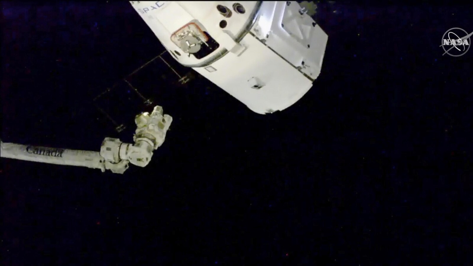 Une capsule spatiale à proximité du bras robotisé de la Station spatiale internationale