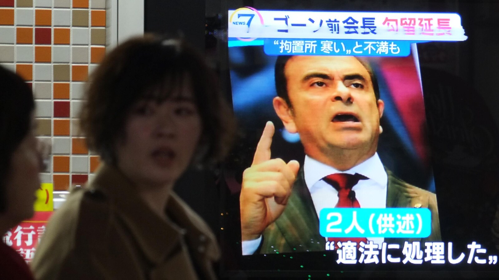 Des femmes japonaises passent devant un écran présentant une image de Carlos Ghosn lors d'un bulletin de nouvelles.