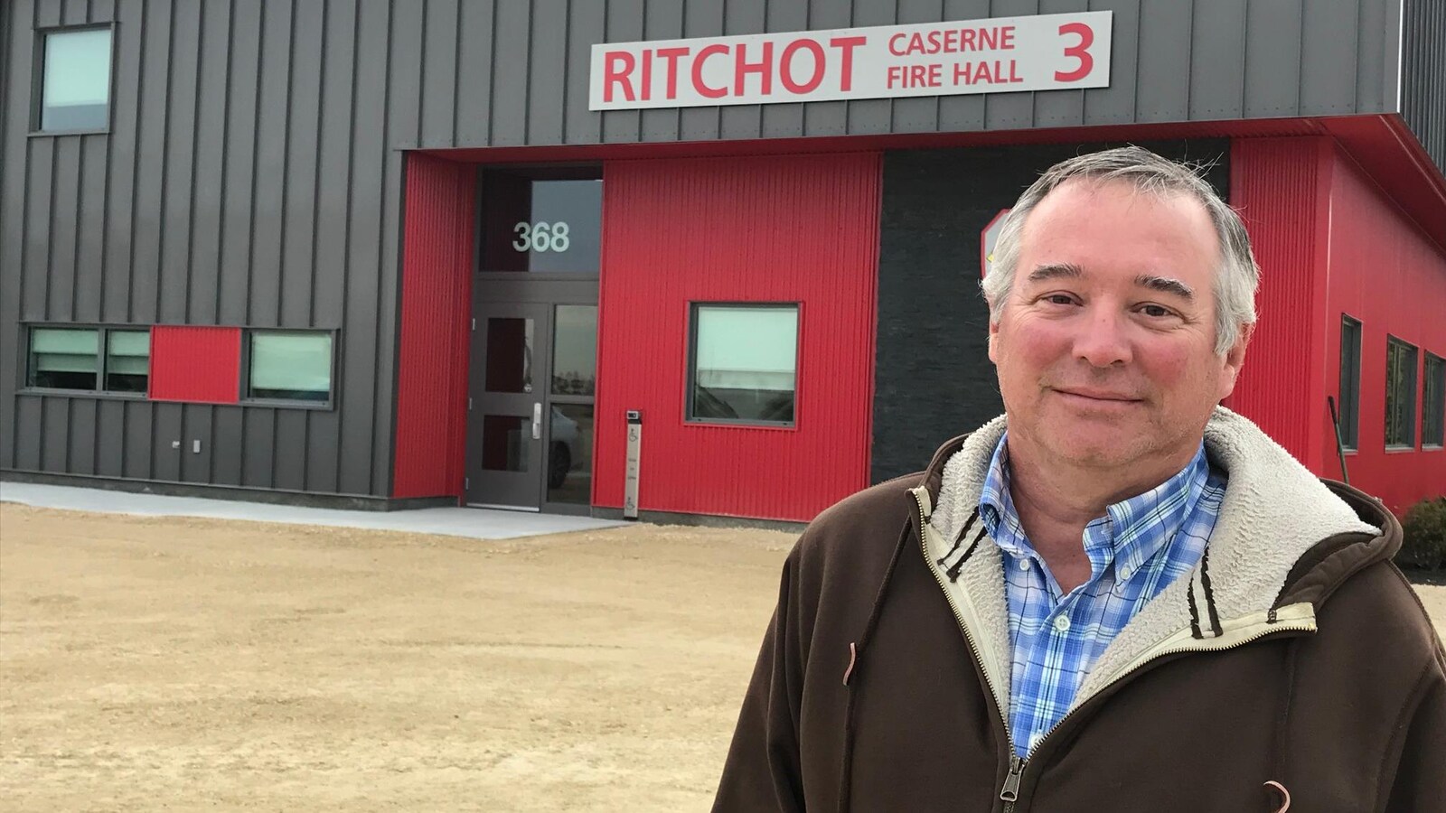 Un homme se tient debout devant une caserne de pompier.