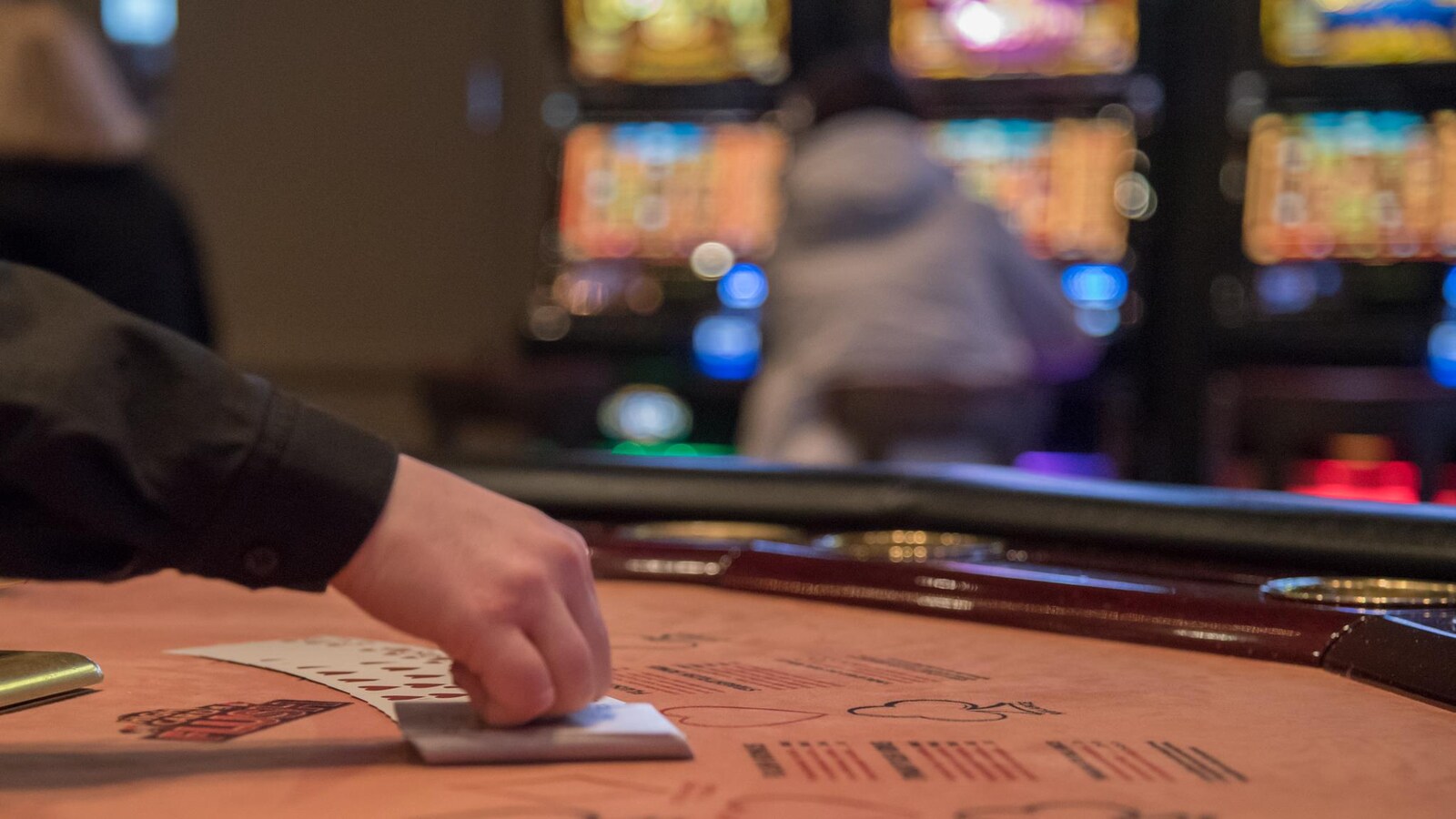 Une main manipule des cartes sur une table de jeu.