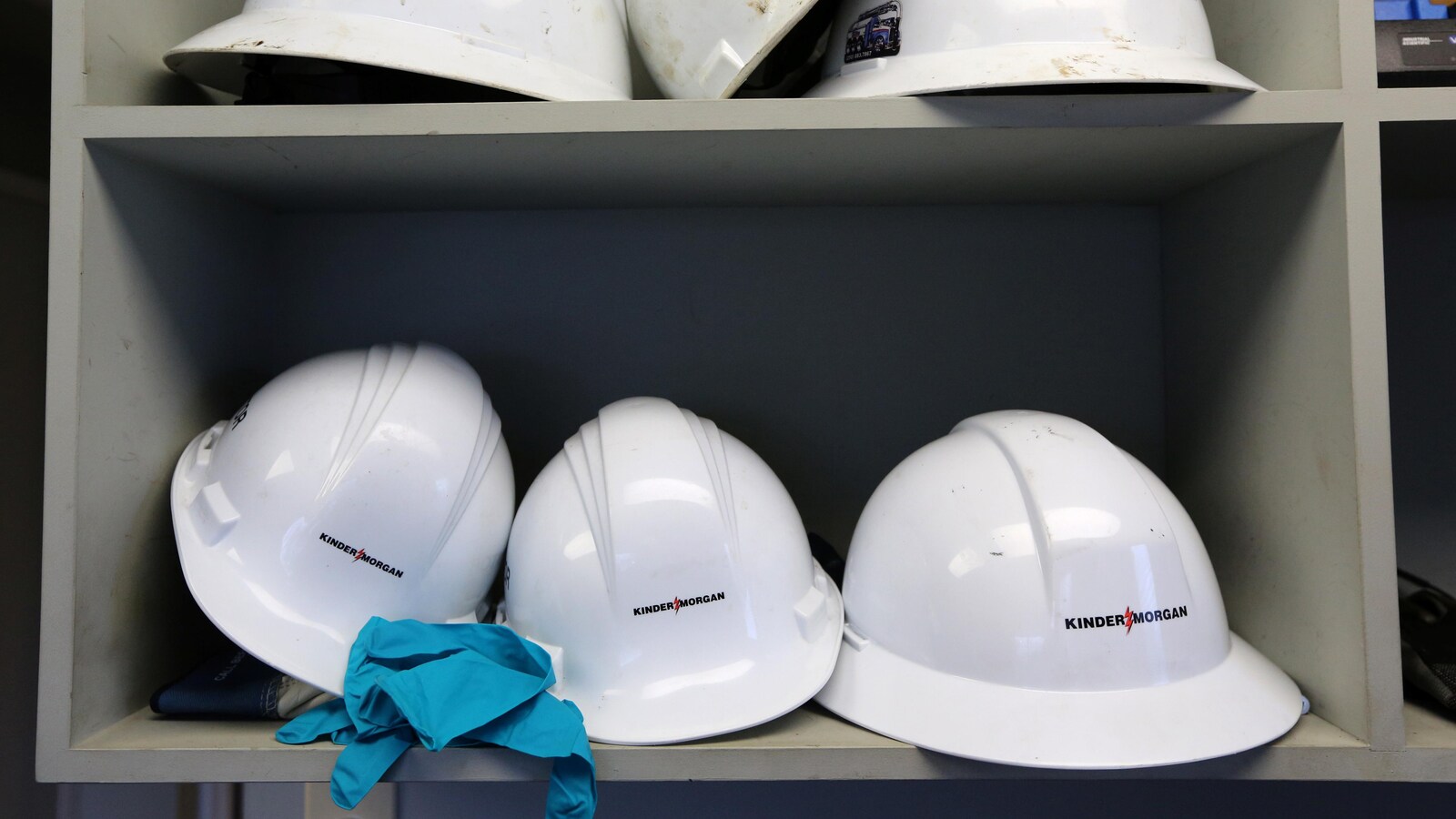 Six casques de protection blancs sont rangés sur deux étagères dans la salle de contrôle de l'entreprise en Colombie-Britannique